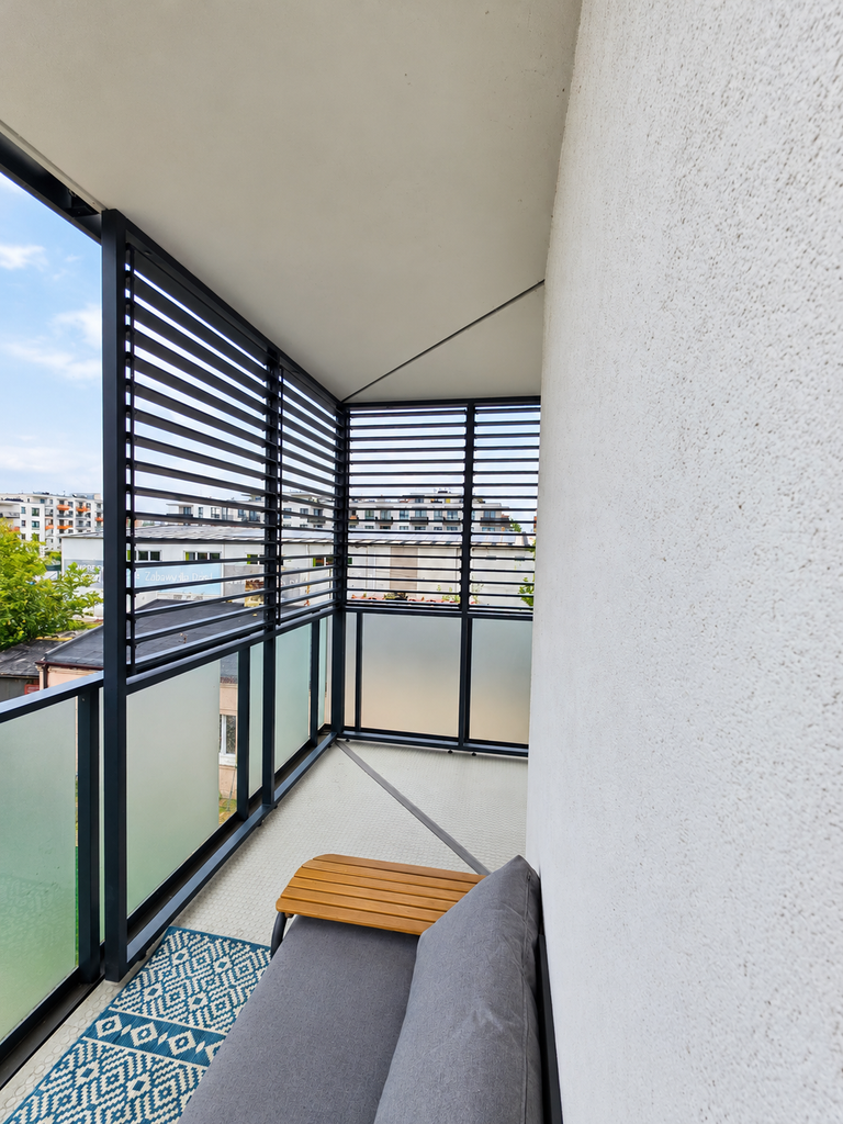 Balcony enclosure in a block of flats; a fixed L-shaped enclosure with OpenUp System retractable patio blinds